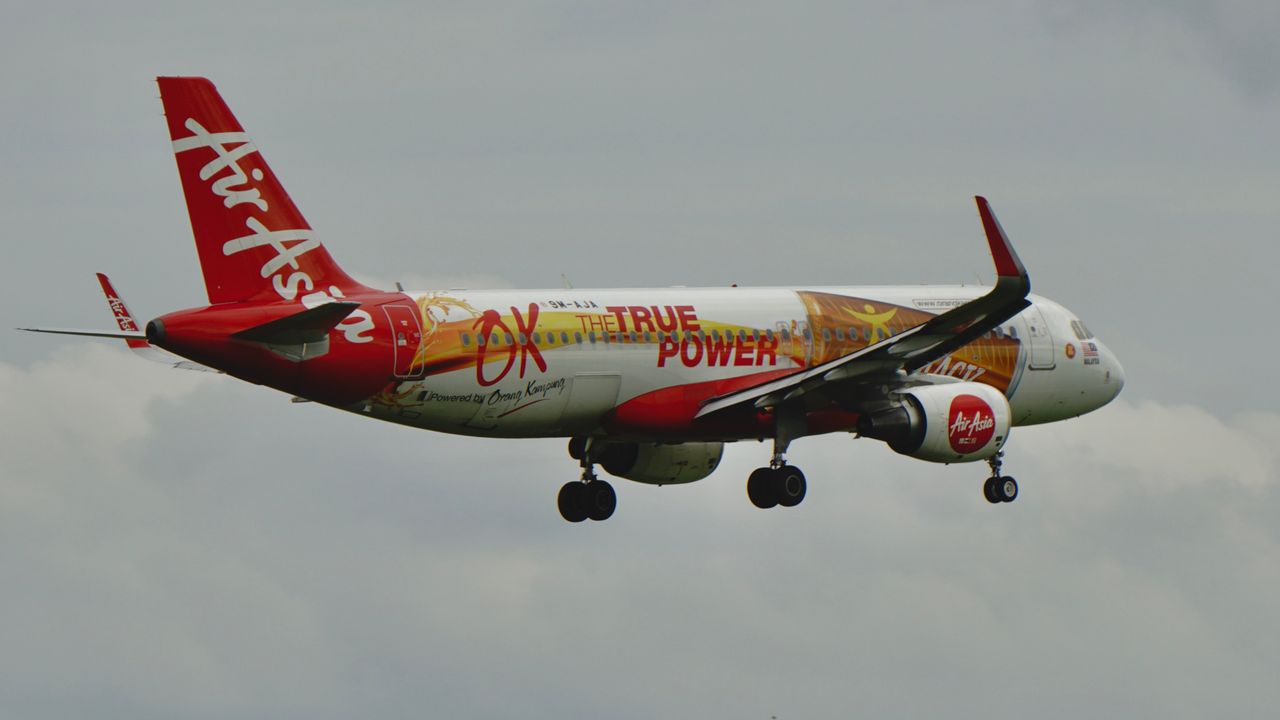 Dynamic AirAsia aircraft flying with unique 'OX The True Power' design.